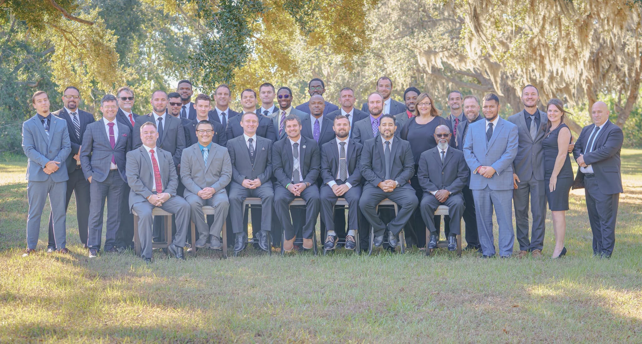 Loving Hands leadership and graduates posed outdoors under oak trees.